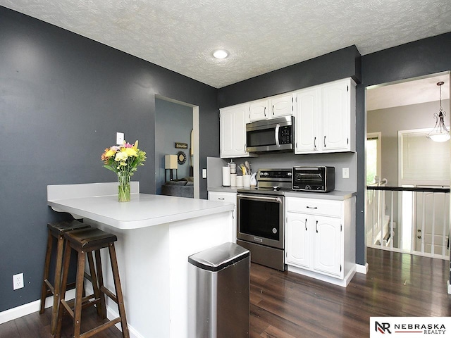 kitchen with stainless steel appliances, dark wood finished floors, white cabinets, baseboards, and light countertops