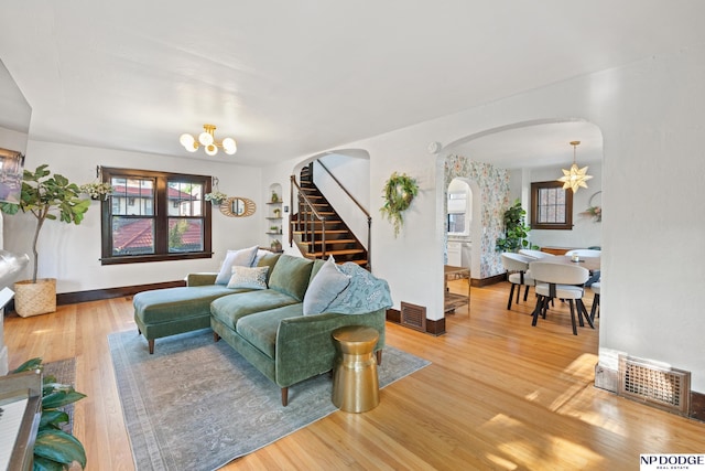 living area featuring a chandelier, arched walkways, wood finished floors, and plenty of natural light