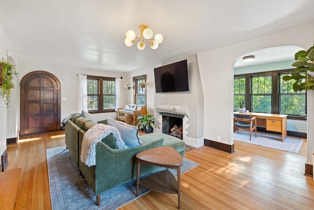 living area with wood finished floors, healthy amount of natural light, arched walkways, and a fireplace
