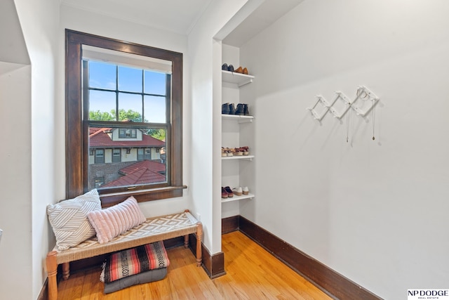 living area featuring light wood-style floors, built in features, baseboards, and crown molding