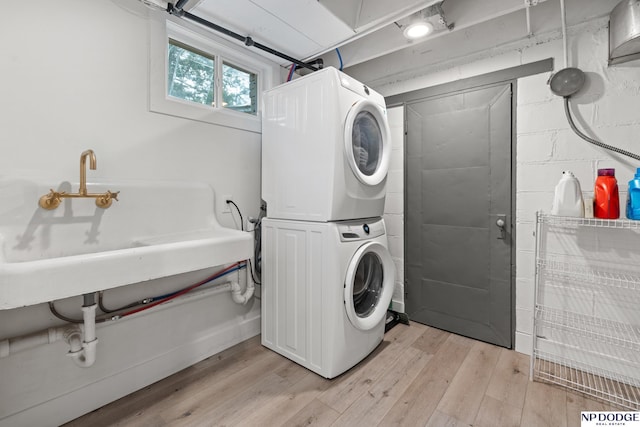 laundry room with stacked washer and clothes dryer and light wood-type flooring