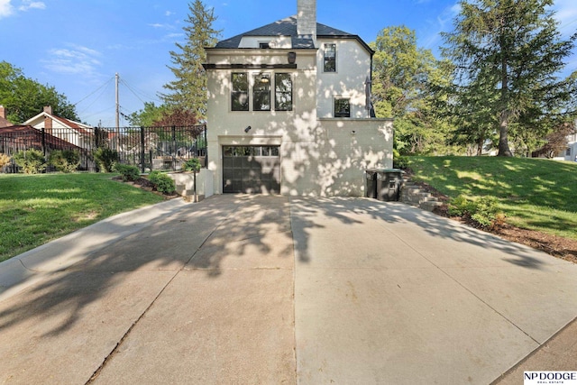 rear view of house with driveway, an attached garage, stucco siding, and a chimney