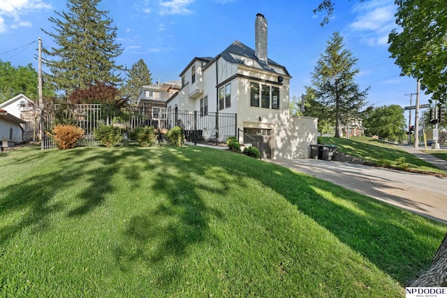 back of property with a chimney, an attached garage, stucco siding, and driveway