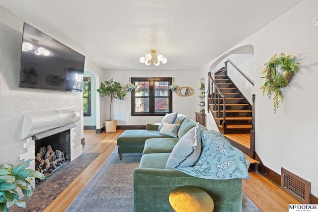 living area with wood finished floors, stairs, arched walkways, and a fireplace