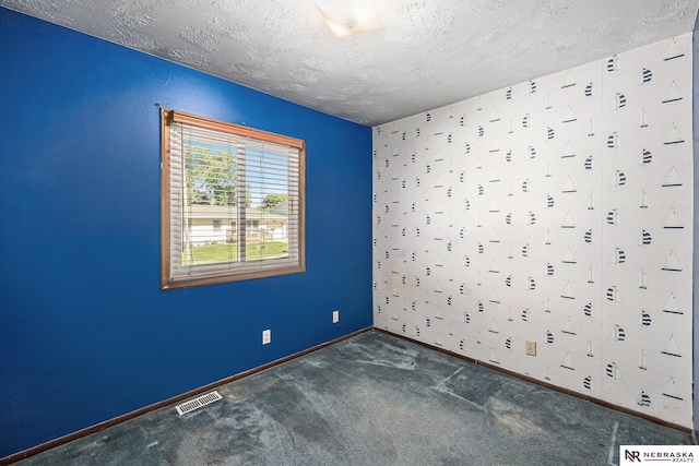 empty room featuring a textured ceiling, baseboards, and carpet flooring