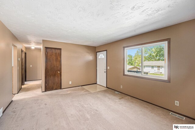 foyer entrance with light carpet, a textured ceiling, and baseboards