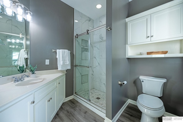full bathroom with a marble finish shower, wood finished floors, baseboards, toilet, and vanity