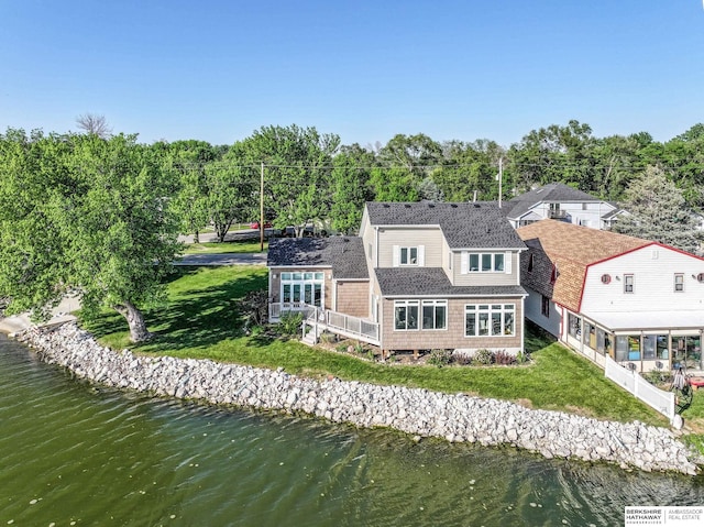 back of property featuring a yard, a shingled roof, and a deck with water view