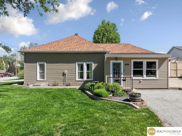 rear view of house with a yard and a shingled roof