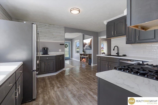 kitchen featuring a sink, freestanding refrigerator, dark wood-type flooring, backsplash, and baseboards