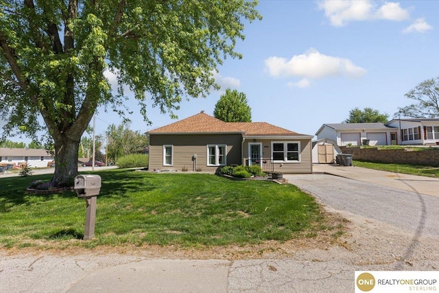 ranch-style house featuring a front lawn, driveway, a shed, an outdoor structure, and a garage