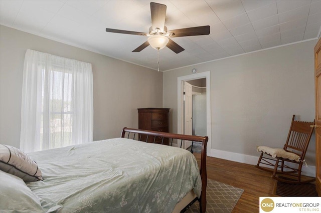 bedroom featuring wood finished floors, baseboards, crown molding, and ceiling fan