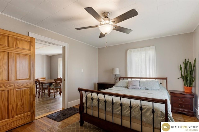 bedroom with wood finished floors, ornamental molding, baseboards, and a ceiling fan