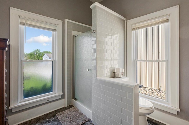 bathroom with a shower stall, toilet, and baseboards