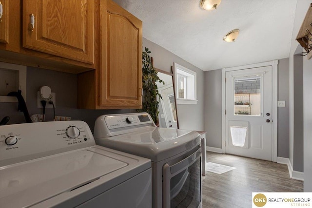laundry area with washer and dryer, cabinet space, baseboards, and light wood-type flooring
