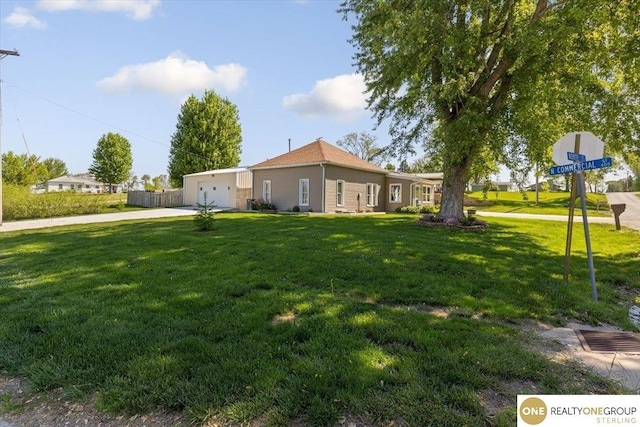 view of green lawn featuring concrete driveway and a garage