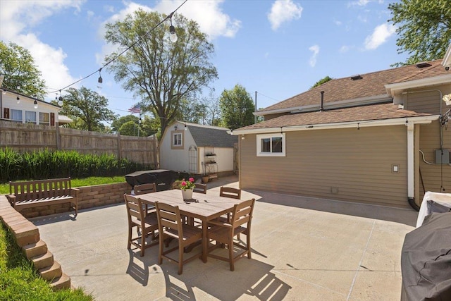 view of patio / terrace with a storage shed, outdoor dining area, fence, and an outdoor structure