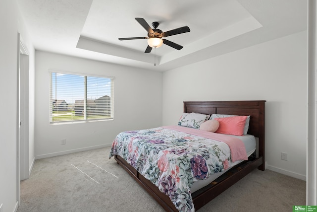 bedroom with a tray ceiling, carpet floors, and baseboards