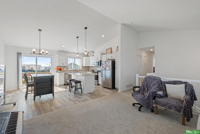 kitchen featuring appliances with stainless steel finishes, a kitchen island, white cabinetry, a kitchen bar, and light countertops