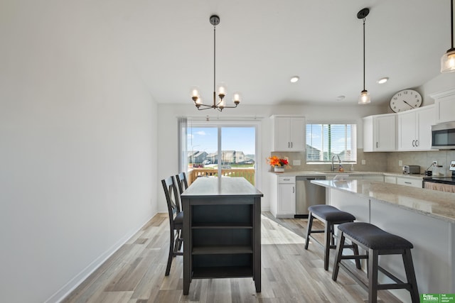 kitchen featuring appliances with stainless steel finishes, a center island, open shelves, a sink, and a chandelier