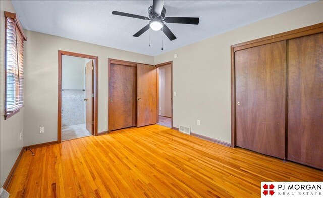 13577 Shirley St, Omaha, NE 68144 - unfurnished bedroom featuring two closets, light wood finished floors, baseboards, connected bathroom, and a ceiling fan