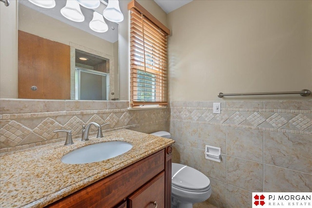13577 Shirley St, Omaha, NE 68144 - full bath with tile walls, a shower stall, vanity, toilet, and wainscoting