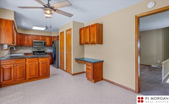 13577 Shirley St, Omaha, NE 68144 - kitchen with stainless steel appliances, a sink, a ceiling fan, brown cabinets, and baseboards