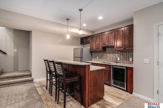 948 S 198th St, Omaha, NE 68022 - kitchen with freestanding refrigerator, wine cooler, a sink, a breakfast bar, and light wood-type flooring