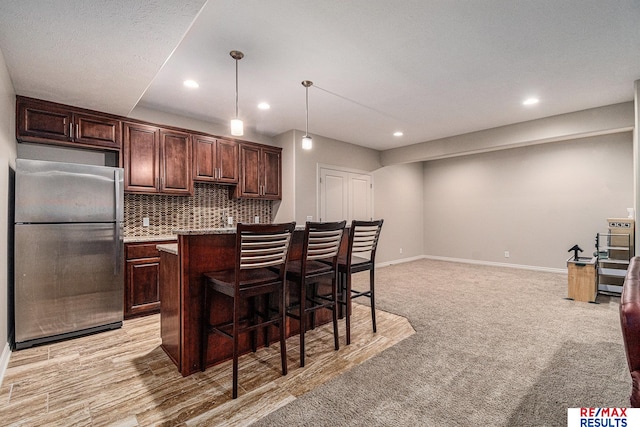 948 S 198th St, Omaha, NE 68022 - kitchen featuring freestanding refrigerator, recessed lighting, a kitchen breakfast bar, light countertops, and decorative backsplash