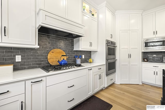 11412 S 122nd St, Papillion, NE 68046 - kitchen featuring stainless steel appliances, white cabinets, backsplash, light wood finished floors, and custom exhaust hood