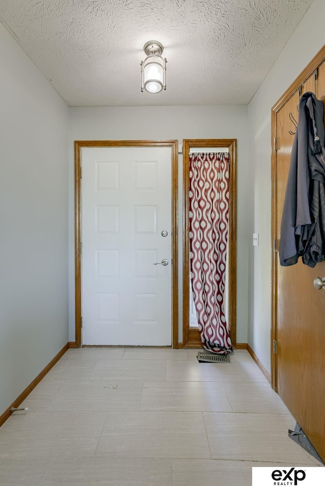 entryway with baseboards and a textured ceiling