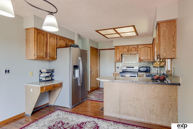kitchen featuring appliances with stainless steel finishes, light wood-type flooring, a peninsula, and tasteful backsplash