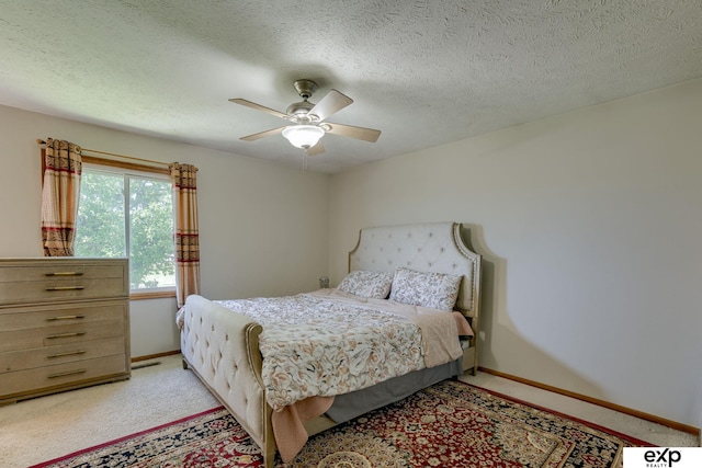 bedroom featuring light colored carpet, baseboards, ceiling fan, and a textured ceiling