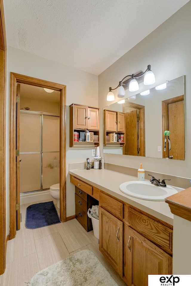 full bath featuring a shower stall, toilet, vanity, and a textured ceiling