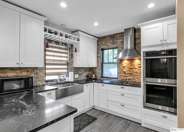 1530 S 52nd St, Omaha, NE 68106 - kitchen with appliances with stainless steel finishes, wall chimney range hood, white cabinets, decorative backsplash, and recessed lighting