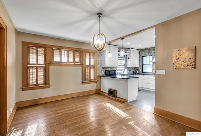 1530 S 52nd St, Omaha, NE 68106 - kitchen with white cabinetry, black microwave, dark countertops, a chandelier, and a peninsula