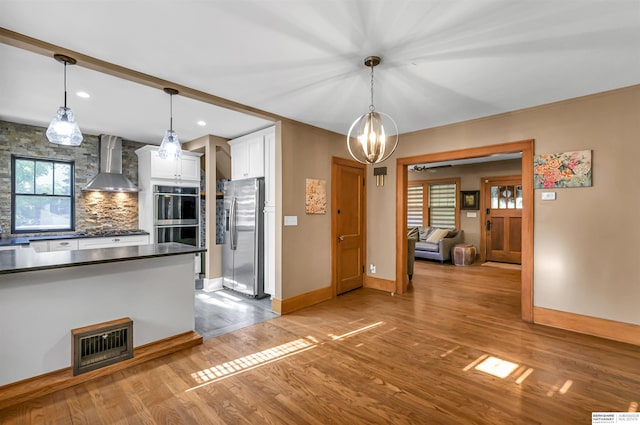 1530 S 52nd St, Omaha, NE 68106 - kitchen with wall chimney range hood, appliances with stainless steel finishes, dark countertops, white cabinetry, and wood finished floors