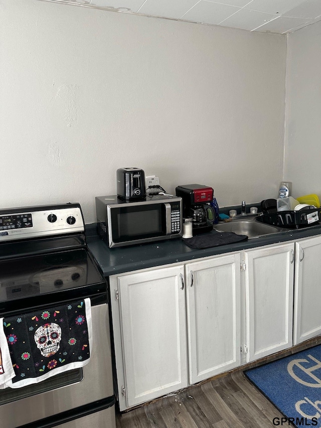 3941 X St, Omaha, NE 68107 - kitchen with appliances with stainless steel finishes, dark countertops, a sink, white cabinetry, and wood finished floors