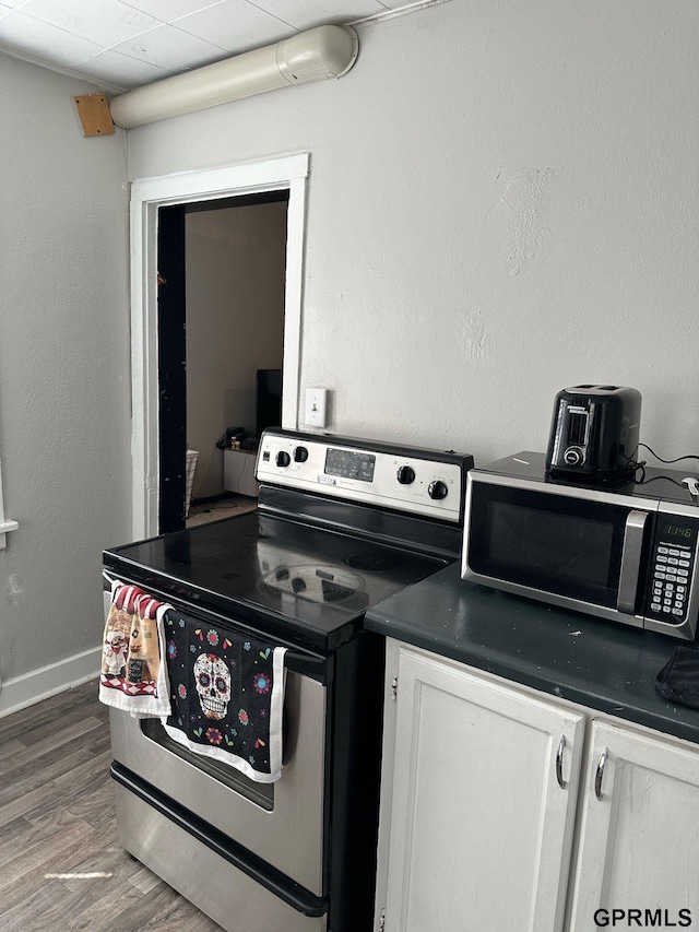 3941 X St, Omaha, NE 68107 - kitchen featuring stainless steel appliances, dark countertops, wood finished floors, and white cabinetry