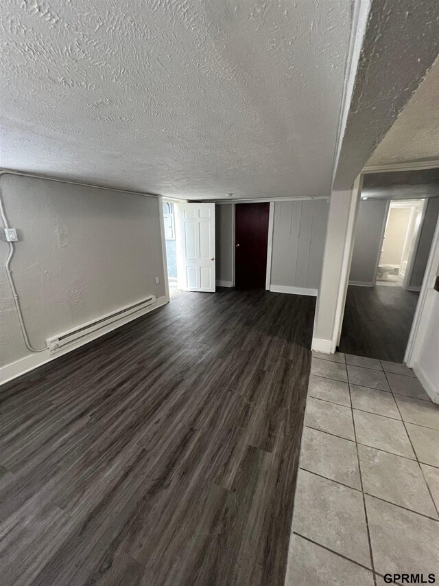 3941 X St, Omaha, NE 68107 - unfurnished living room with baseboard heating, wood finished floors, a textured ceiling, and baseboards
