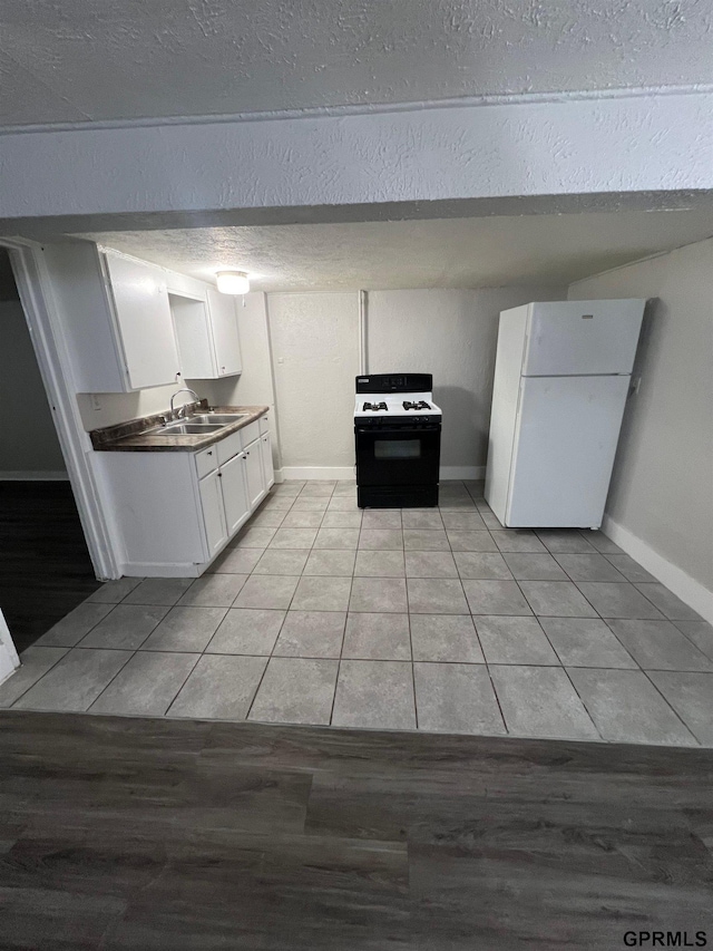 3941 X St, Omaha, NE 68107 - kitchen with gas range oven, freestanding refrigerator, white cabinetry, a sink, and light tile patterned floors