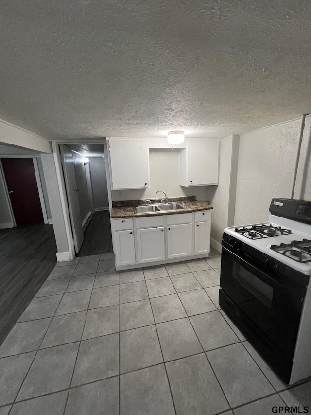 3941 X St, Omaha, NE 68107 - kitchen with gas range, a sink, white cabinets, light tile patterned flooring, and dark countertops