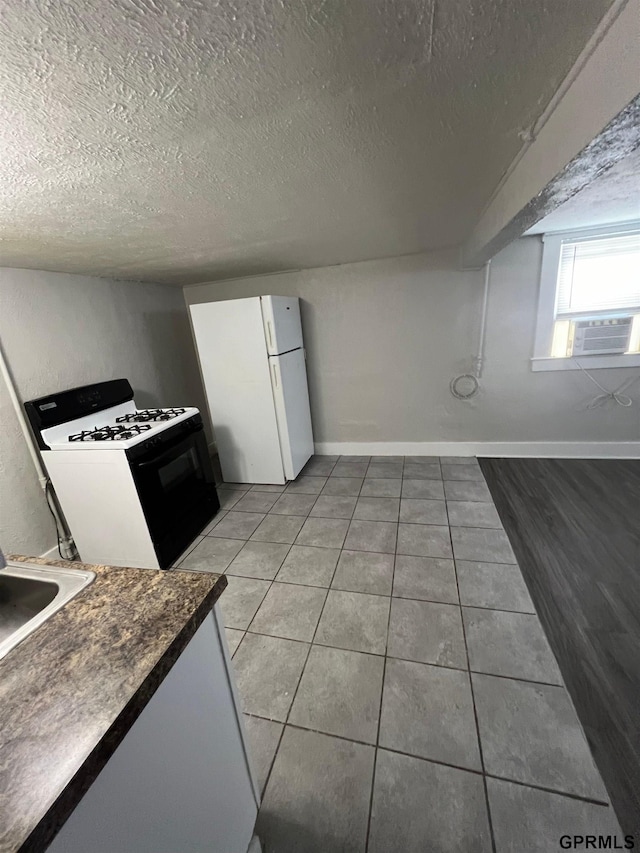 3941 X St, Omaha, NE 68107 - kitchen featuring range with gas cooktop, freestanding refrigerator, cooling unit, light tile patterned flooring, and dark countertops