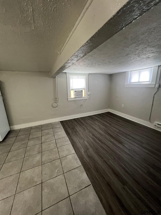3941 X St, Omaha, NE 68107 - below grade area with a textured ceiling, wood finished floors, fridge, baseboards, and cooling unit