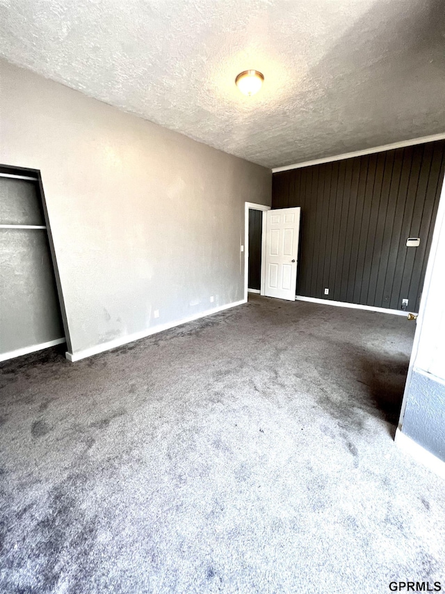 3941 X St, Omaha, NE 68107 - unfurnished bedroom with a textured ceiling, carpet, baseboards, and wooden walls