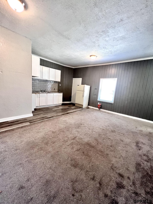 3941 X St, Omaha, NE 68107 - unfurnished living room with a textured ceiling, carpet flooring, baseboards, and wooden walls