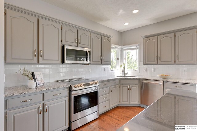 9901 S 176th St, Omaha, NE 68136 - kitchen with appliances with stainless steel finishes, a sink, gray cabinets, light wood finished floors, and recessed lighting