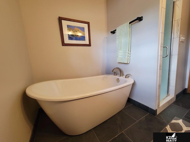 full bath featuring a shower stall, a soaking tub, tile patterned floors, and baseboards