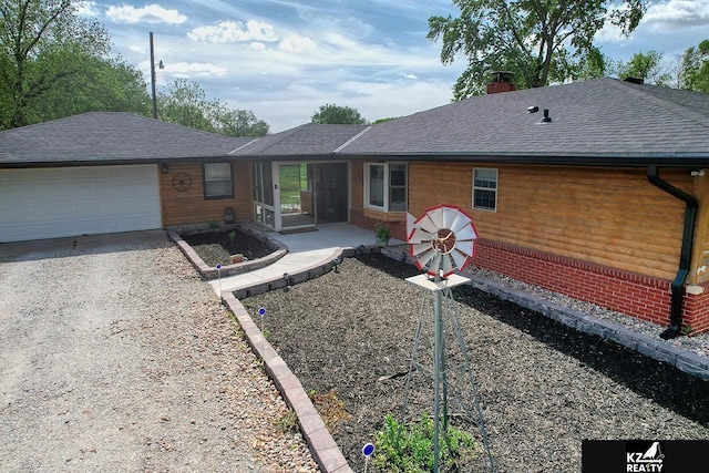 ranch-style home featuring a chimney, driveway, a garage, and roof with shingles