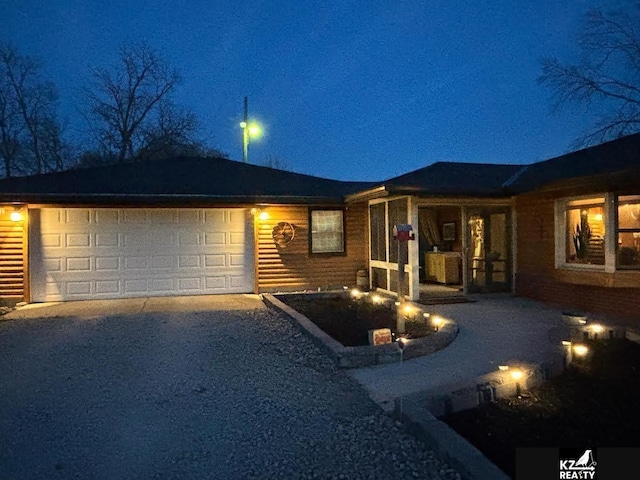 ranch-style house with gravel driveway and a garage